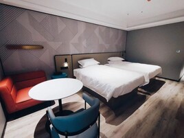 Una habitación de hotel con cama, sofá rojo, mesa redonda y silla azul.