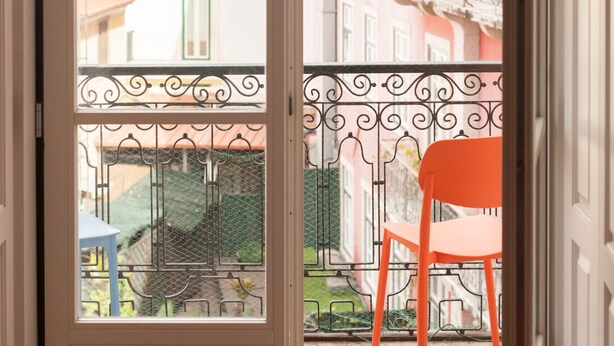 A balcony with a chair, a wrought iron railing, and a view of buildings. - FLH Restauradores Bright & Chic Flat with Balcony (Lisboa ciudad)