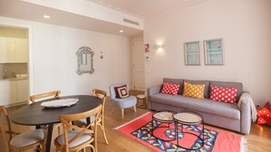 A living room with a sofa, chairs, a dining table, and a patterned rug. - FLH Restauradores Bright & Chic Flat with Balcony (Lisboa ciudad)