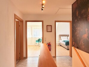 A hotel room with a bed, a chair, a table, and a painting on the wall.