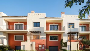 A multi-story residential building with balconies, a gated entrance, and a small garden area.