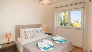 A hotel room with a bed, nightstands, a lamp, and a window with curtains.