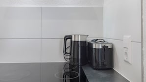 Una cucina con un piano di lavoro nero, un bollitore in acciaio inossidabile e un tostapane.