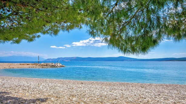 A pebble beach with clear water, distant mountains, and a lighthouse. - Ultra-modern vacation home for 6 with swimming pool in Crikvenica (Crikvenica)