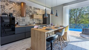 A modern kitchen with a wooden island, pendant lights, and a view of the outdoors. - Ultra-modern vacation home for 6 with swimming pool in Crikvenica (Crikvenica)