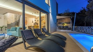 A modern outdoor lounge area with a pool, seating, and a glass-enclosed dining space. - Ultra-modern vacation home for 6 with swimming pool in Crikvenica (Crikvenica)