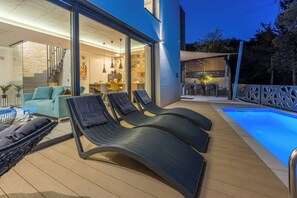 A modern outdoor lounge area with a pool, seating, and a glass-enclosed dining space. - Ultra-modern vacation home for 6 with swimming pool in Crikvenica (Crikvenica)