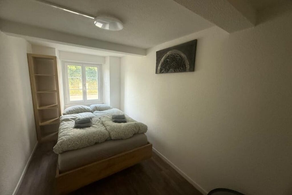 Une chambre à coucher avec un lit, une fenêtre, une œuvre d’art accrochée au mur et une échelle en bois.