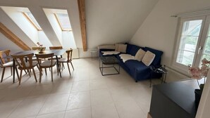 Une pièce de style loft comprenant un coin repas, un canapé et des fenêtres de toit.