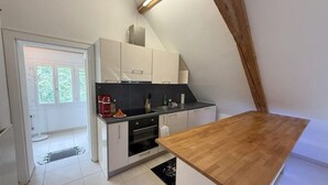 Une cuisine compacte avec des meubles blancs, un plan de travail en bois et un four encastré.