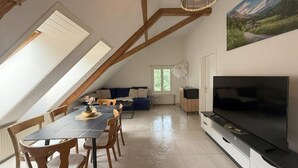 Un coin repas avec une table et des chaises, un canapé, un téléviseur et un tableau accroché au mur.