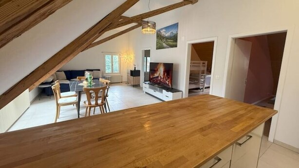 Un vaste loft doté d’une table à manger en bois, d’une cheminée et offrant une vue sur l’extérieur.