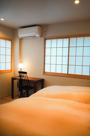 Habitación de hotel con cama, escritorio, silla, aire acondicionado y ventana con vistas.