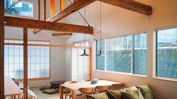 A traditional Japanese-style room with tatami flooring, a low wooden table, and a green sofa. - Kogawa House  (Nozawaonsen)