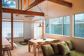 Una habitación al estilo japonés tradicional, con suelo de tatami, una mesa de madera baja y un sofá verde.
