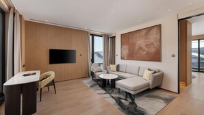 A modern living room with a sofa, armchairs, a coffee table, a flat-screen TV, and a large window. - Club Med UO Hangzhou Longwu Resort (Hangzhou)
