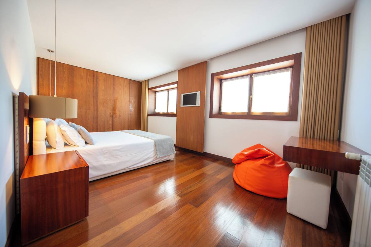 Une chambre moderne avec un lit, des tables de chevet, une fenêtre et un panneau mural en bois.