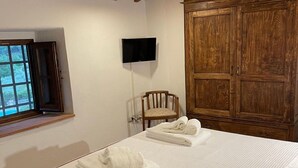 Un dormitorio con cama, un armario de madera, un televisor montado en la pared y una ventana.