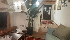 Una sala de estar con chimenea, una planta en maceta, un sofá y una mesa de comedor.