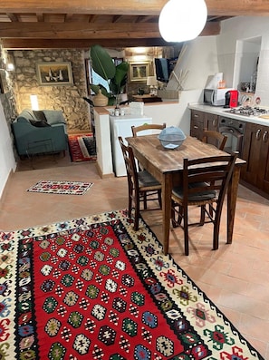 Une cuisine chaleureuse avec une table à manger, des chaises, un réfrigérateur et un téléviseur.