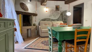Un comedor acogedor con una mesa verde, una silla de madera, un sofá y una chimenea.