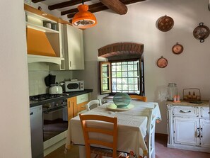 Una cocina con una mesa de comedor, sillas, estufa, microondas y ventana con vistas.