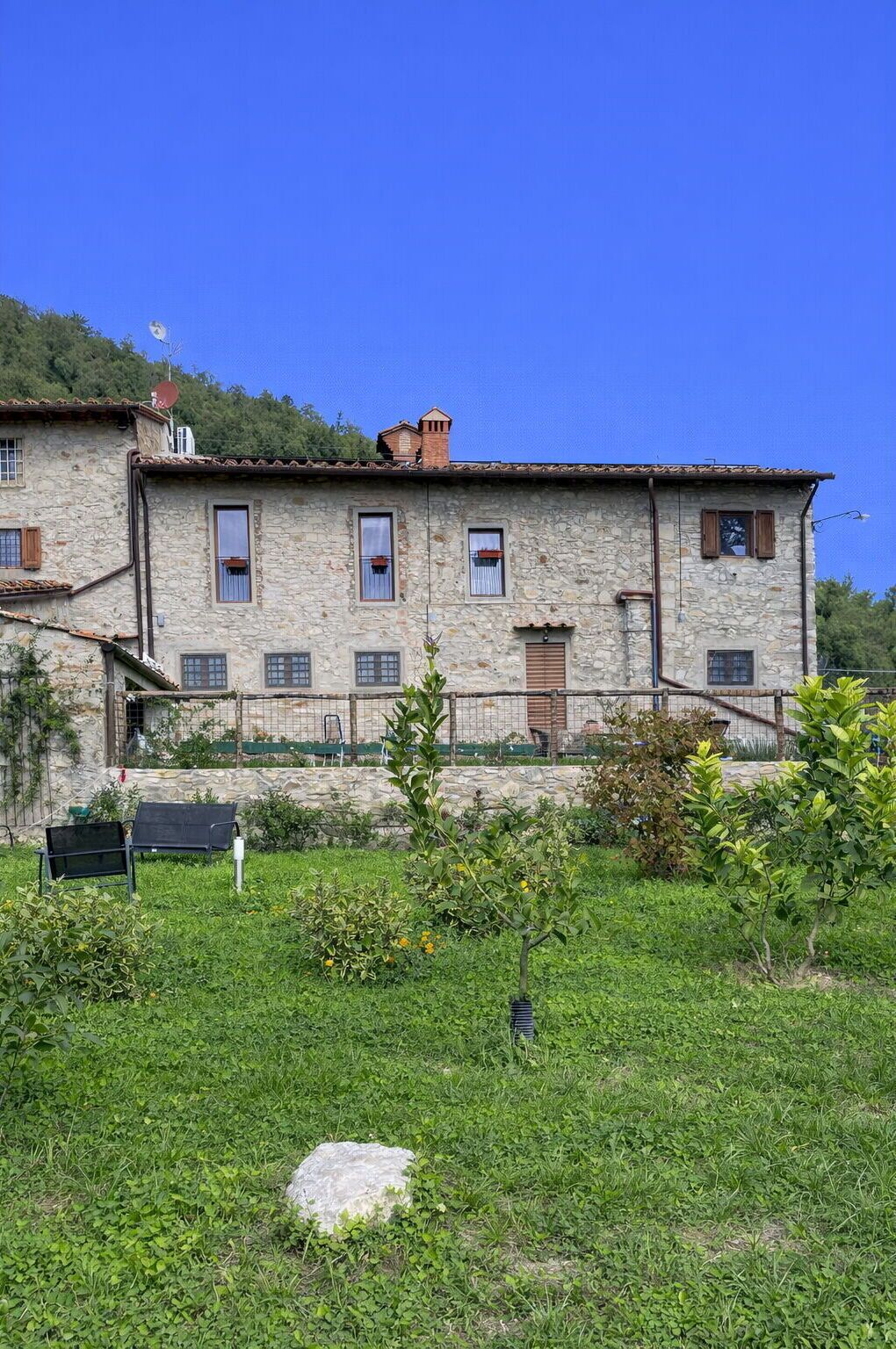 A stone building with multiple windows and a small garden in front.