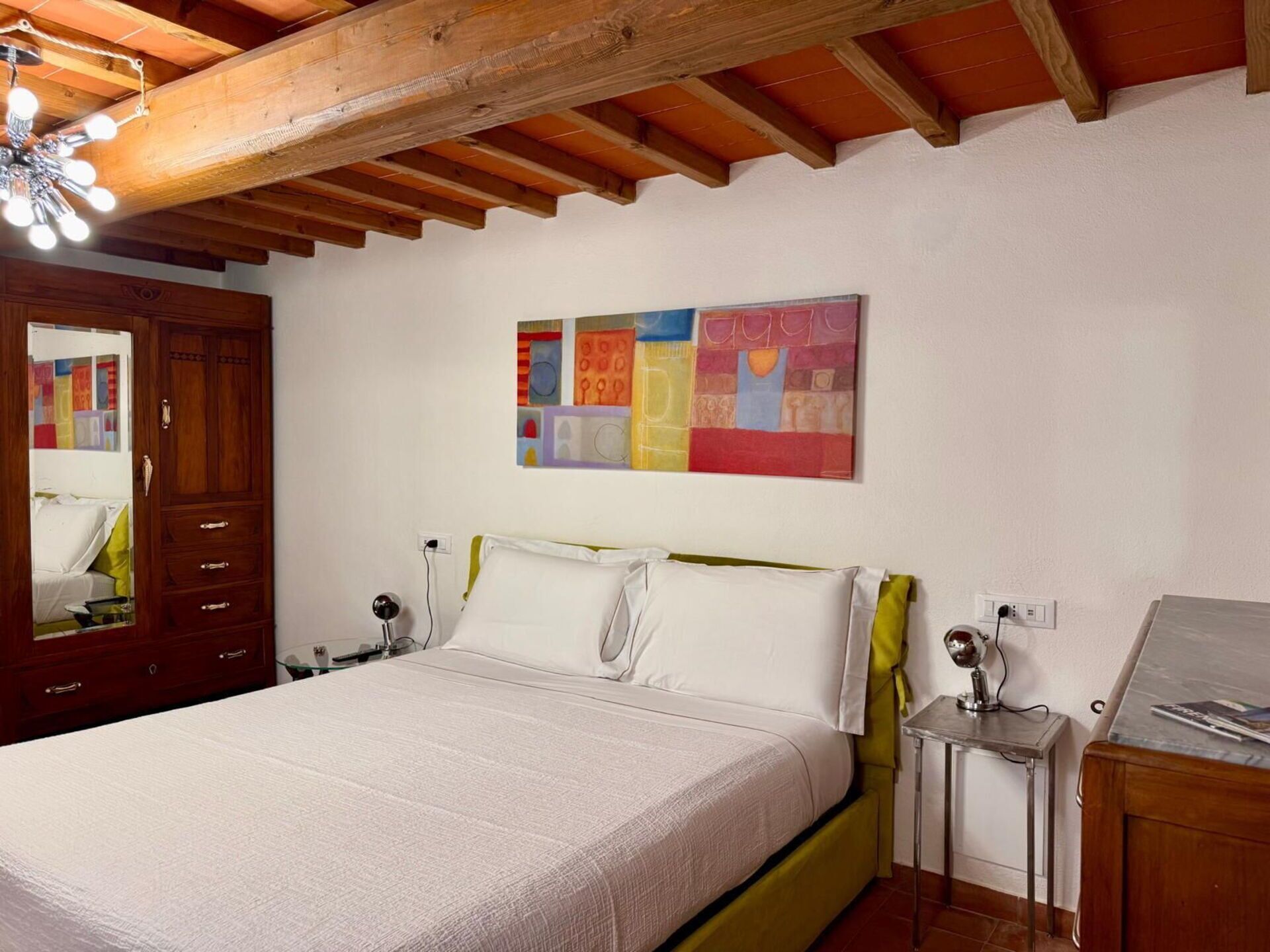 A bedroom with a bed, bedside tables, a mirror, and a ceiling fan.