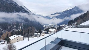 Un village de montagne enneigé, avec des maisons et une vue dégagée sur la vallée.