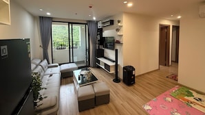 Una sala de estar moderna con un sofá, una mesa de centro, un televisor y un balcón con cortinas.