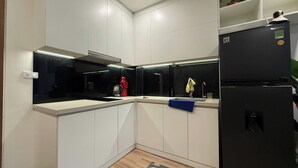 Una cocina moderna con armarios blancos, un refrigerador negro y un horno empotrado.