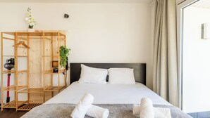 Una habitación de hotel con una cama, un armario de madera, una planta y toallas sobre la cama.