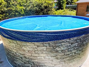Una piscina circular con revestimiento de piedra y el interior azul.