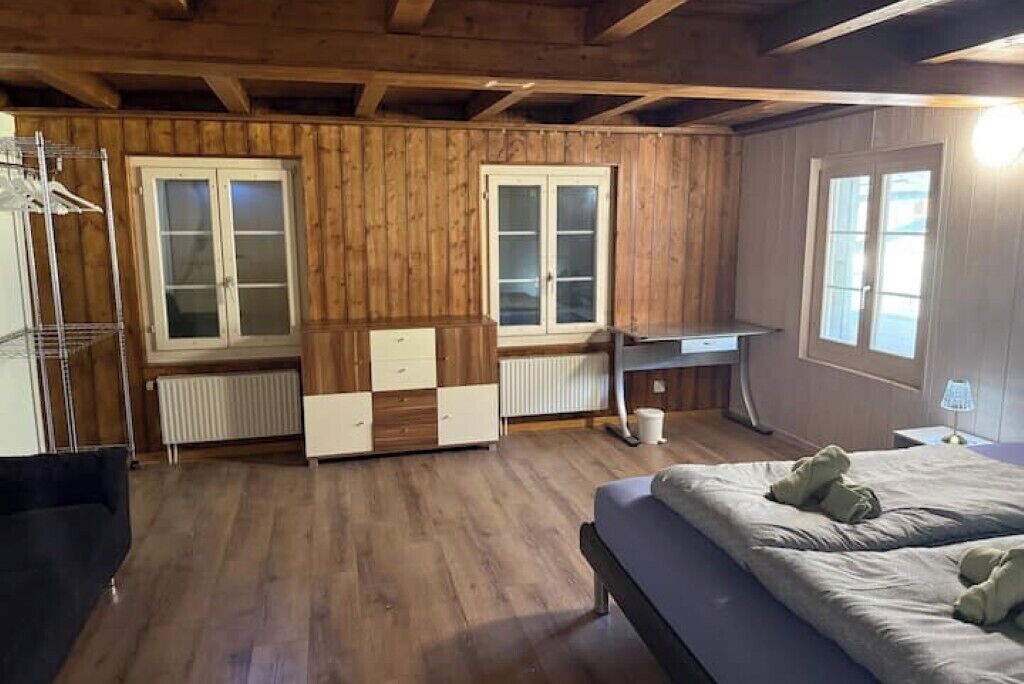 Una stanza con rivestimento in legno, un letto, una scrivania e un termosifone.