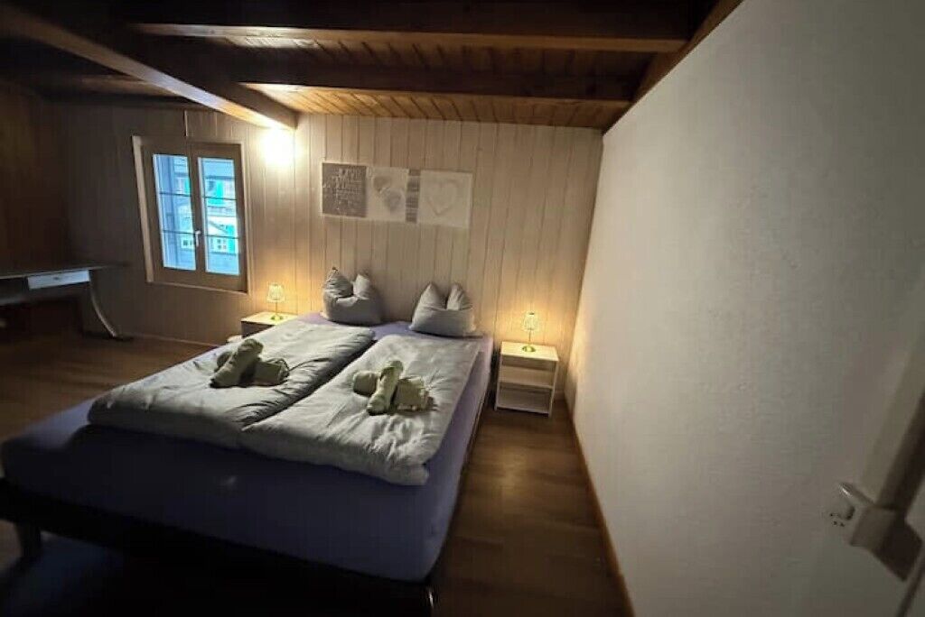 A bedroom with a bed, two bedside tables, a nightstand, a window, and a wall with a poster.
