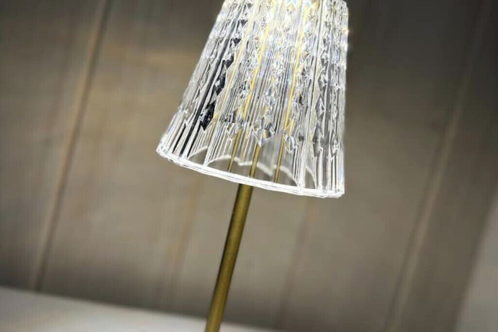 A lamp with a clear, textured shade on a gold stand.