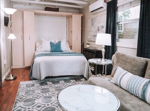 A bedroom with a bed, a round coffee table, a sofa, and a lamp. - Charming studio with AC perfect for a relaxing getaway (Tampa)