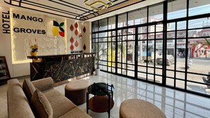 A hotel lobby with a reception desk, sofas, and large windows offering a view of the street.