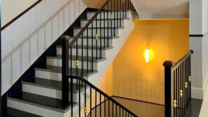 A staircase with black railings and a light fixture on the wall.