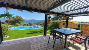 A covered outdoor area with a pool, a table with chairs, and a view of mountains. - Luxurious cottage with private pool and spa in the Canebières estate in Le Muy. (Le Muy)