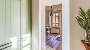 En hall med en grön dörr, ett matområde med ett bord och stolar samt en hängande lampa.