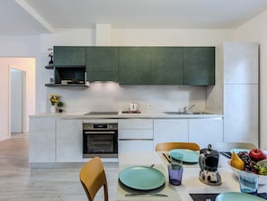 A modern kitchen with built-in appliances, a dining area with a table set for two, and a view of the adjacent living space. - Lovely apartment for 6 guests with TV and balcony (Dongo)