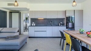 Eine moderne Küche mit Kochinsel, grauen Schränken und einem Essbereich mit Holztisch und Stühlen.