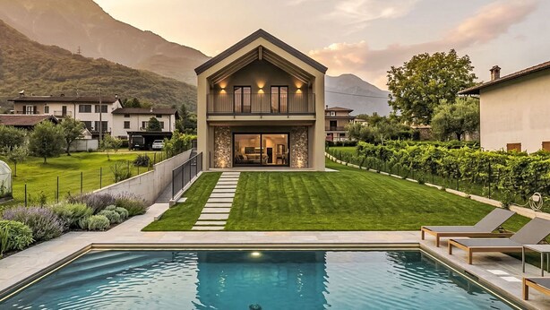 Ein modernes, zweistöckiges Haus mit Swimmingpool und gepflegtem Rasen.