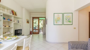 Une pièce comprenant une table à manger, des chaises, un téléviseur, un canapé et des œuvres d’art accrochées aux murs.