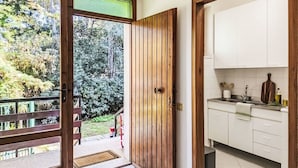 Une cuisine moderne avec des meubles blancs, un évier et une fenêtre donnant sur un jardin.