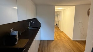 A modern kitchen with white cabinets, a black countertop, and a wooden floor. - Happy Life 2-20min Interlaken-Panoramic view of mountains (Wimmis)