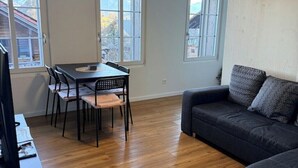 A room with a dining table, chairs, a sofa, and a television. - Happy Life 2-20min Interlaken-Panoramic view of mountains (Wimmis)