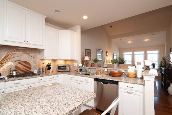 A spacious kitchen with white cabinetry, granite countertops, and a dishwasher. - Waterfront Resort | Community Amenities | Sleeps 13 (Selbyville)