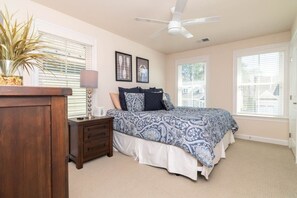 A bedroom with a bed, bedside table, lamp, and a ceiling fan. - Waterfront Resort | Community Amenities | Sleeps 13 (Selbyville)